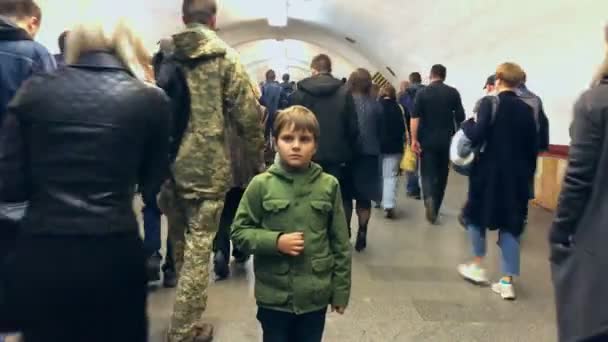 녹색 자켓을 입고 지하 통로에서 관중 가운데서 있는 어린아이. — 비디오