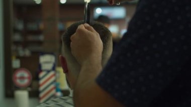 Berber makasıyla saç kesimi ve arkasında berber logosu olan tarak. Erkeklerin elleri kuaförde kestiriyor.. 