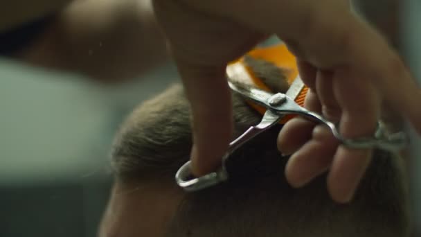 Primer plano de los hombres corte de pelo por tijeras peluqueros y peine en cámara lenta. Manos de hombre haciendo corte de pelo masculino en el salón . — Vídeos de Stock