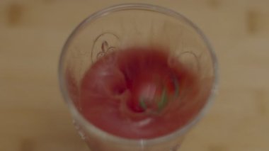 Küçük domatesin yavaşça kırmızı domates suyunun içine düşmesi. Domates suyu spreyi üst görünümü. 