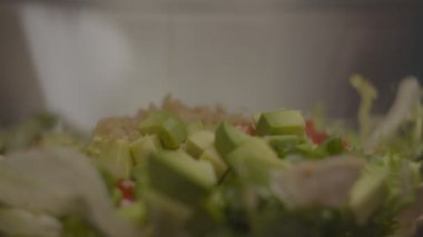 Quinoa 'nın cam kaseye domatesli taze salata ve yavaş çekimde tavukla uçtuğunu yakın çekim. Salata yapma süreci. 