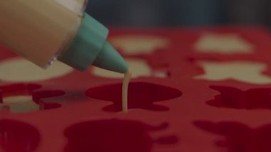 Krema enjektöründeki hamurlar kırmızı silikon pişirme kabına dökülüyor. Glüten ve şekersiz kurabiye pişirmek. Zencefilli kurabiye.. 