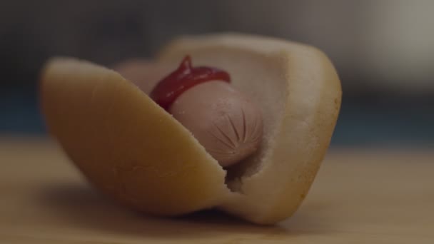 Гаряча собака з ковбасою всередині на дерев'яній обробній дошці. Кумедний наливний кетчуп . — стокове відео