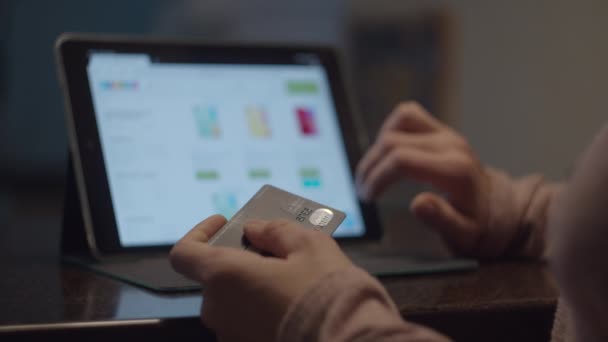 Vrouwelijke handen die een debetkaart vasthouden en online winkelen op de tablet computer. Vrouw kiezen gadgets op internet winkel en kopen in slow motion. — Stockvideo