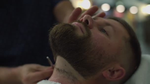 Barberos manos afeitar mans barba en el cuello con cuchilla de afeitar en cámara lenta, vista lateral . — Vídeos de Stock