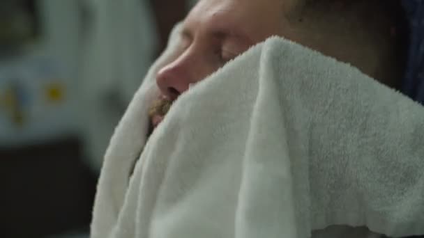 Zbliżenie fryzjerów ręce suszenie broda mans z białym ręcznikiem w fryzjera w zwolnionym tempie. — Wideo stockowe