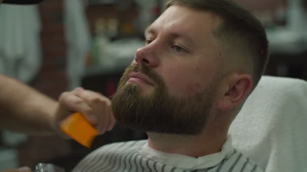 Бородатый человек и парикмахеры руки бритья бороду с помощью электробритья машины и расческа в замедленной съемке. Мужчина с закрытыми глазами в парикмахерской . — стоковое видео