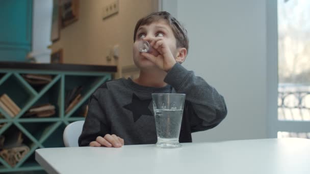 Autistico ragazzo della scuola che prende pillole e capsule di vitamine e bere bicchiere d'acqua al rallentatore . — Video Stock