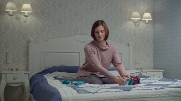 Ung kvinna vuxen kvinna fällbar färg strumpor sitter på sängen. Marie Kondo metod för att organisera och förenkla hemmet. — Stockvideo