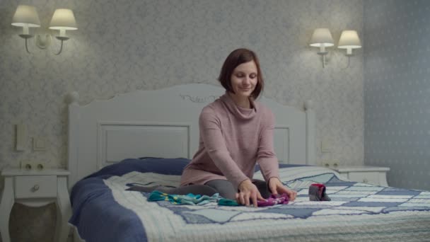 Mujer joven mujer adulta plegable calcetines de color sentados en la cama. Marie Kondo método de organizar y simplificar el hogar . — Vídeos de Stock