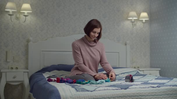 Молодая взрослая женщина складывает цветные носки, сидя на кровати. Метод Мари Кондо по организации и упрощению дома . — стоковое видео