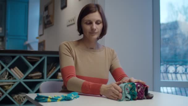 Masada oturan, renkli çorapları katlayan genç kadın. Marie Kondo ev düzenleme ve sadeleştirme yöntemi. — Stok video