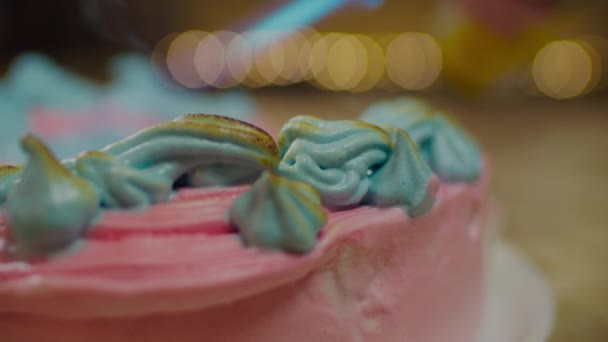 Gâteau rose rotatif avec fleur de meringue bleue flamboyante au ralenti avec lumières de fond floues . — Video