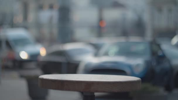 Main féminine mettant tasse en papier avec boisson chaude sur la table en bois de la rue. Boisson chaude au café urbain froid et venteux . — Video