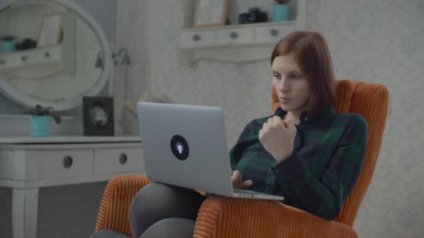 在笔记本电脑上工作的自由女作家坐在卧室舒适的橙色扶手椅上。 在家里做小玩意的女人. — 图库视频影像