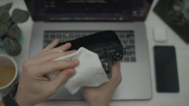 Erkeklerin elinde klasik fotoğraf makinesi. Peçeteyle kamerayı silen adam. Masasında aletler olan üst görünüm. 