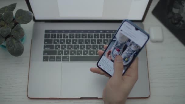 Mans hands surfing online by cell phone and drinking coffee. Вид сверху ноутбука, смартфона, наушников и чашки кофе на столе . — стоковое видео