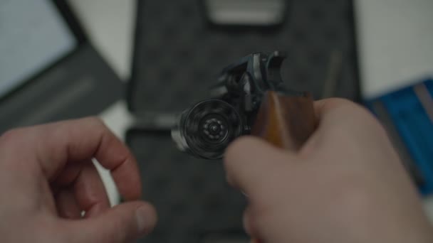 Man holding handheld revolver and cleaning it. Male hands testing pistol after cleaning, turning gun drum. Close up top view — Stock Video