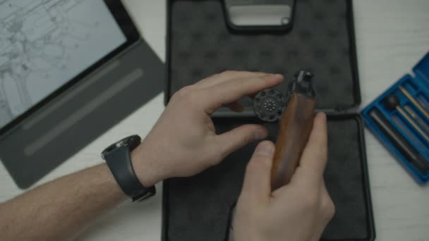 Man holding handheld revolver and cleaning it. Male hands testing pistol before cleaning. Top view of mans desk. — 비디오