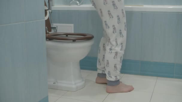 Жінка в піжамі сидить на туалеті у синій ванній кімнаті. Жінка приходить і сидить на туалеті . — стокове відео