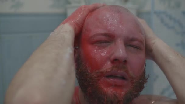 Bald bearded man taking shower to wash off blood. Blooded man standing in bathroom under water pressure. — 비디오