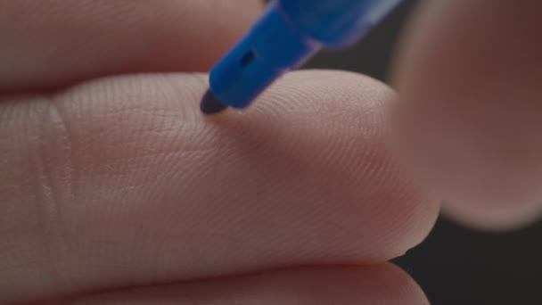 Написання синього щасливого смайлика на паличці, макропогляд. Рука з синім маркером малює щасливі емодзі на пальцях . — стокове відео