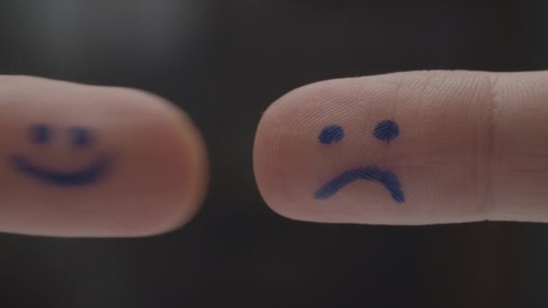 Zwei Finger mit glücklichen und traurigen Smileys auf Fingerkissen, die sich begegnen und interagieren. glückliche traurige Emotionen in Zeichen. Makrosicht. — Stockvideo