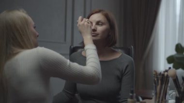 Makyaj için başvuran iki bayan arkadaş. İş yerindeki iş kadını için vize başvurusu. Masada bir sürü kozmetik ve fırça var..