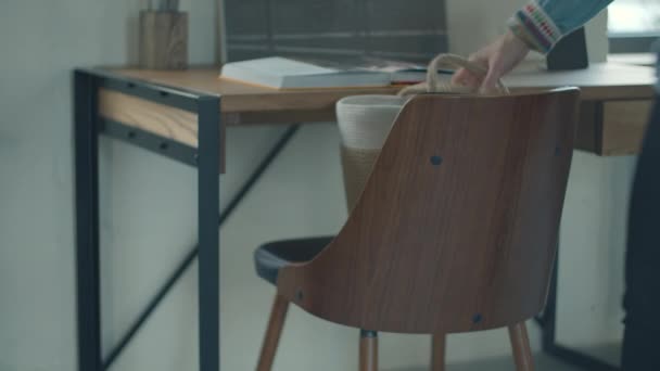 Mujer tomando bolso ladys de sillón de madera. Mesa de madera con libro abierto y sillón con bolsa de hembras . — Vídeo de stock