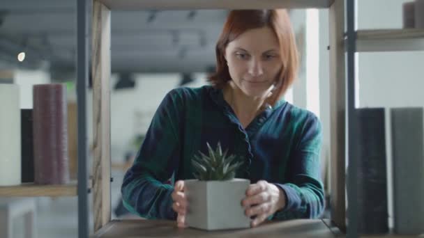 Gelukkig dansen en zingen in de kaars als een microfoon vrouw zet items thuis aan het recht. Lilt vrouwelijke zetten kaarsen en potten aan planken. — Stockvideo