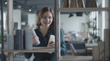 Happy dancing and singing into the candle like a microphone woman putting items at home to rights. Lilt female putting candles and pots to shelves. 