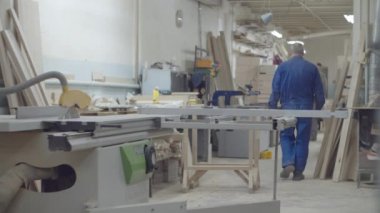 Marangozlar makinelerle ahşap fabrikasında çalışıyorlar. Tahta mobilya üretim süreci. Marangozluk atölyesinin yeri. 