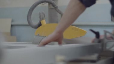Carpenter working on a circular saw machine. Wooden furniture manufacturing process. Carpentry workshop. Man working with wood and saw. 