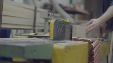 Woodworker male hands holding timber and taking to woodworking machine. Carpentry workshop processes. Wooden furniture manufacturing