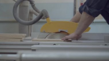 Carpenter working on a circular saw machine. Wooden furniture manufacturing process. Carpentry workshop. Man working with wood and saw. 