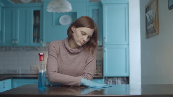 Young 30s exhausted female spraying detergent and wiping table surface with rag. Upset and tired woman making home clean up on kitchen. — Wideo stockowe