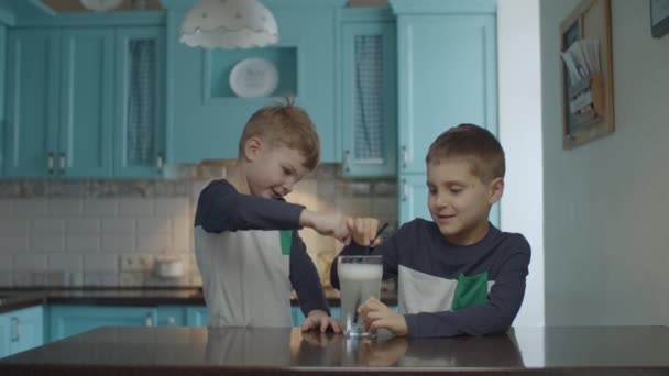 Kids drinking homemade soda with bubbles through drinking straw. Brothers enjoying beverage on the kitchen. 