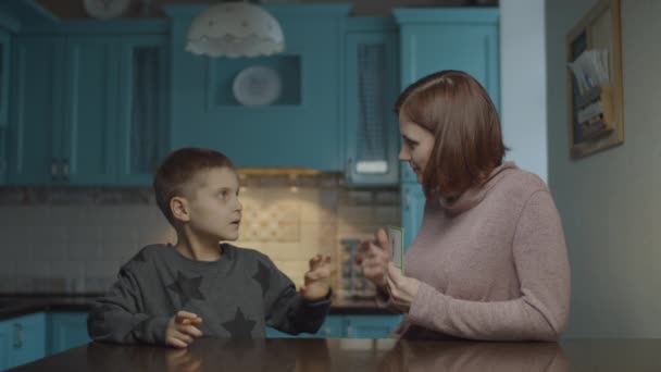 Мати викладає аутистичну дитину з картками вдома. Малюк з аутизмом навчальний номер з матір'ю, що показує освітні картки на кухні . — стокове відео