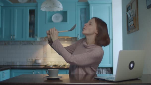 Happy female dancing and singing into kitchenware like a microphone on domestic blue kitchen. Woman dancing emotional on the kitchen. Scoop as microphone. — Stock Video