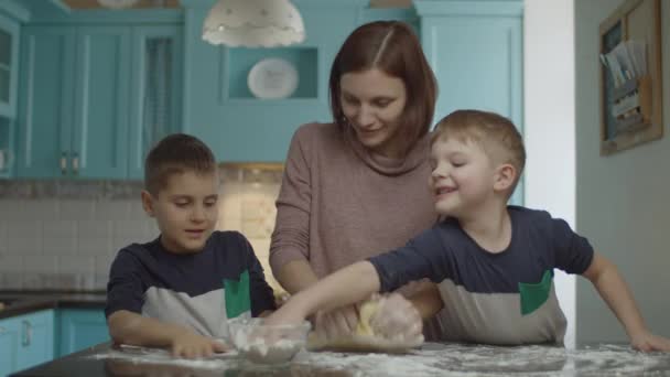 Feliz familia divirtiéndose con harina mientras se cocinan galletas. Niños ayudando a la madre a amasar la masa y jugar con harina en la cocina azul . — Vídeos de Stock