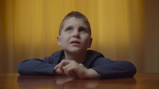 Retrato de menino autista mostrando emoções sentadas na mesa. Miúdo com autismo a sentir-se frustrado em casa. Consciência do autismo — Vídeo de Stock