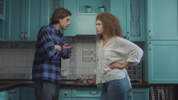 Jeune couple de 20 ans se disputant debout sur la cuisine bleue à la maison, petit ami criant petite amie accusatrice. Conflit familial jaloux . — Video