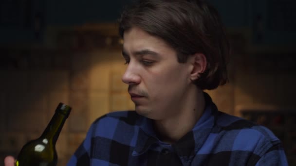 Close up portrait of depressed young 20s man drinking wine of bottle. Upset male in blue shirt drinking wine and choking in fist. — Stock Video