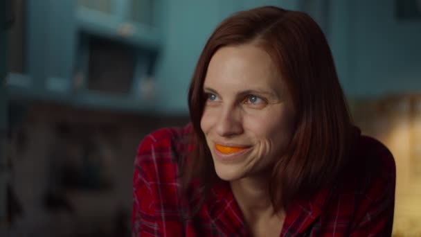 Detailní záběr mladé třicátnice hrající si s pomerančovými slupkami v ústech. Usmívající se samice s pomerančovým ovocem v puse. Oranžový úsměv. — Stock video