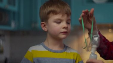 Anneler, oğlunun öksürük, grip ya da virüsleri tedavi etmesi için maske takmasına yardım ediyor. Çocuğun solunumunu ilaçla kapat.. 