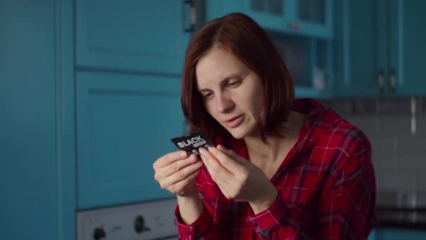 Ung 30-talskvinna i röd skjorta läser instruktioner för kosmetisk mask på blått kök. Kvinna skönhet rutin hemma. — Stockvideo