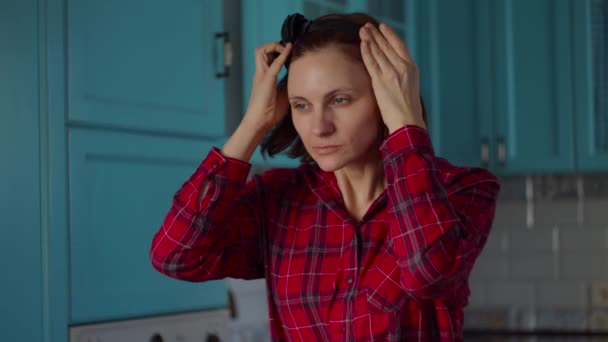 Mulher de 30 anos usando aro preto na cabeça e, em seguida, aplicando máscara cosmética branca em seu rosto. Mulher rotina de beleza em casa na cozinha azul . — Vídeo de Stock