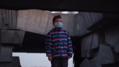 Tıbbi koruyucu maskeli çocuk Coronavirus COVID-19 salgını sırasında sığınakta duruyor ve etrafı izliyor. Koronavirüsle savaşmak için ulusal acil durum ve sıkıyönetim. 