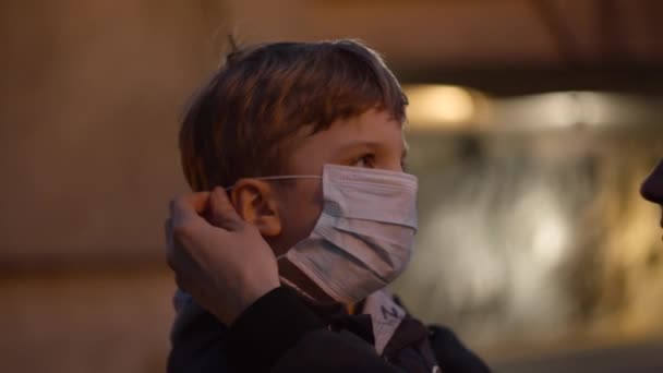 Mother wearing medical protective mask on sons face in shelter during pandemic outbreak of coronavirus COVID-19. Emergency siren with red light outdoors. — Stock Video