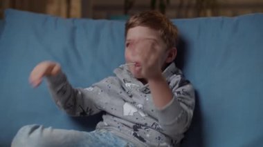 Ağzında lolipopu olan genç bir çocuk akşamları rahat bir kanepede oturan annesine beş dolar veriyor. Annem evde oğullarına el çırpıyor.. 